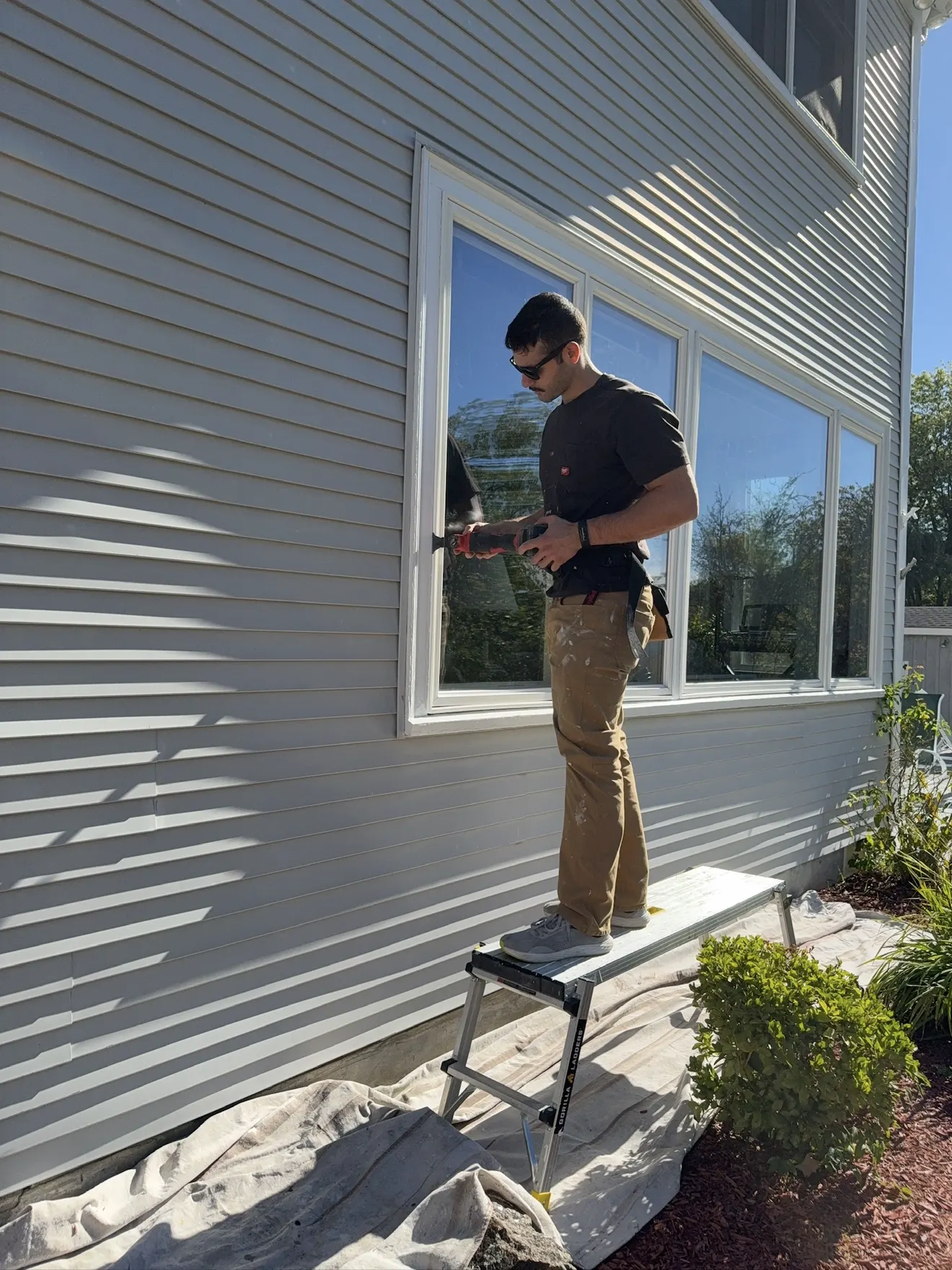 Proper Paint crew member sealing a window over a drop cloth before the final coat