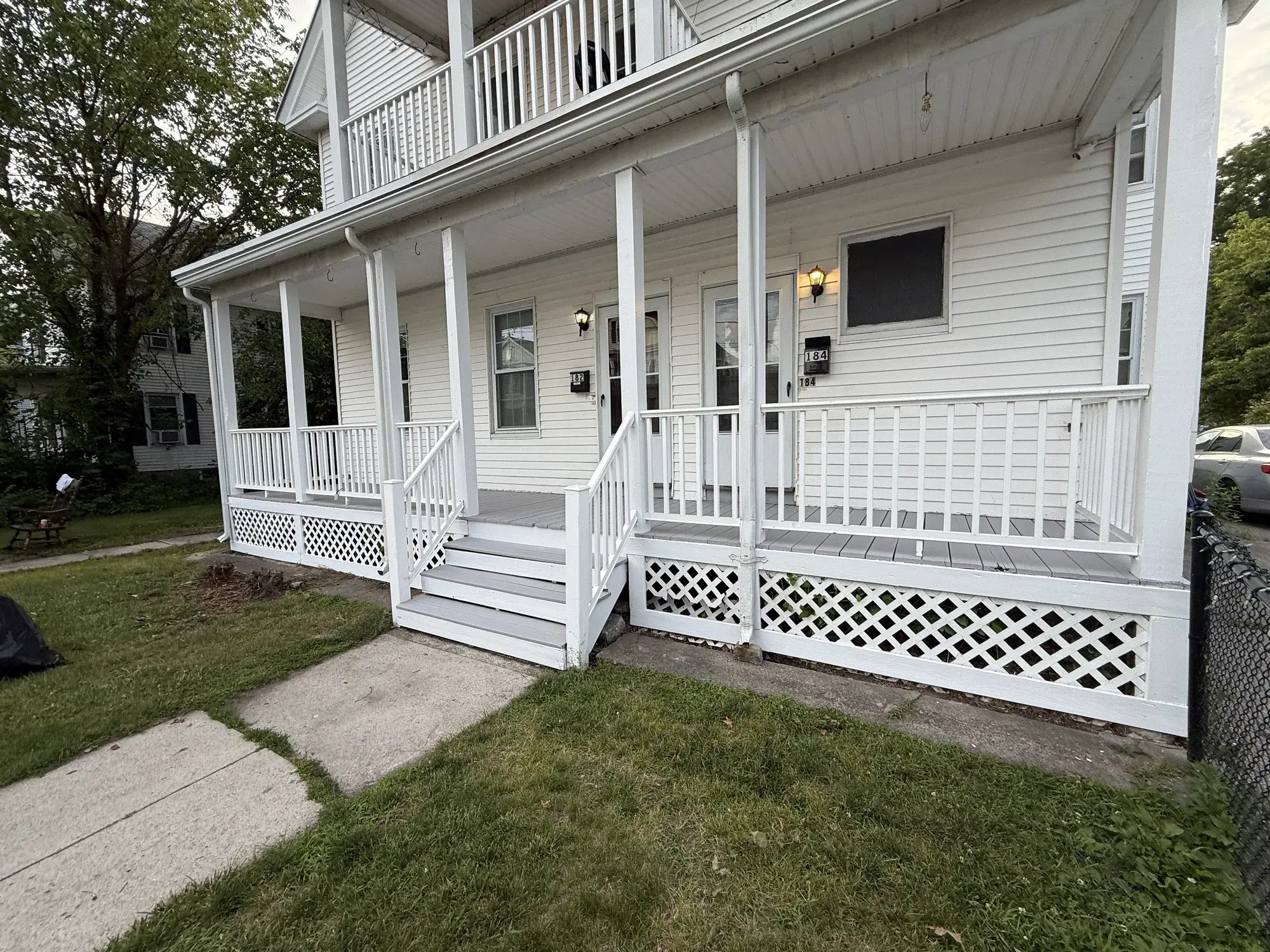 A real Proper Paint porch project: freshly painted white steps, railings, lattice skirting and siding